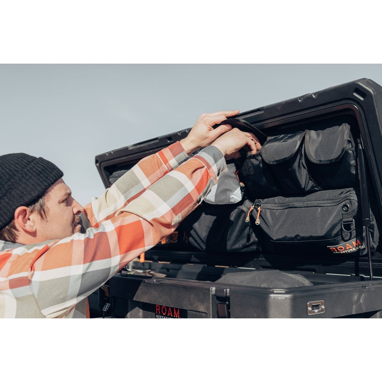 Man arranging gear and tools using the lid organizer in an 83L Rugged Case